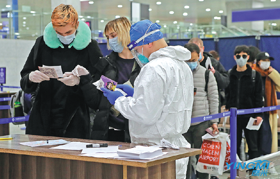 A customs officer checks passengers' health information at Pudong International Airport in Shanghai. (Photo by Yin Liqin/China News Services)